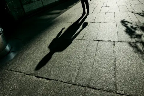 Sombra de pessoa na calçada à noite